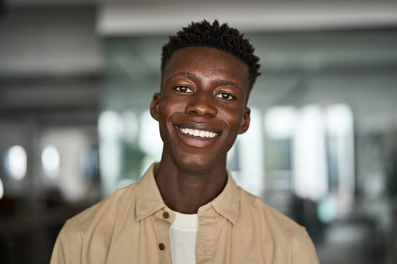 Close up portrait of young happy African man student looking at camera. Headshot
