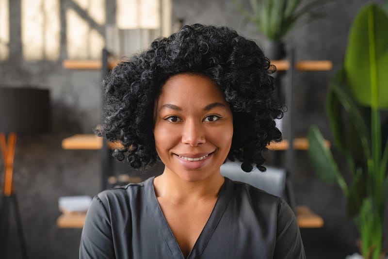 Happy young African business woman head shot portrait. Corporate worker looking at camera
